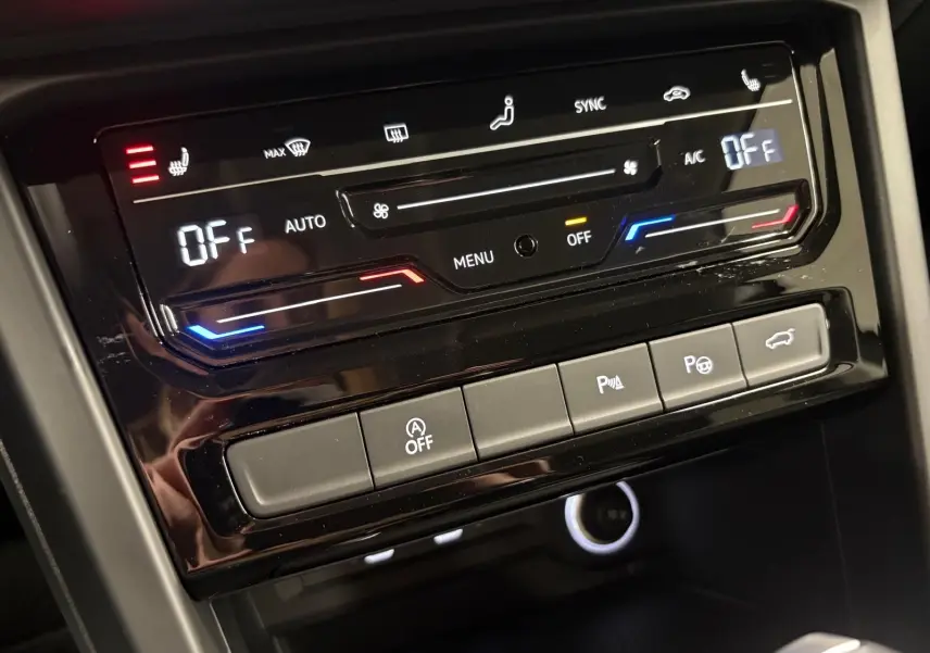 Panneau de commande de climatisation et assistances dans l’habitacle du Volkswagen Touran gris Dauphin, vue rapprochée.