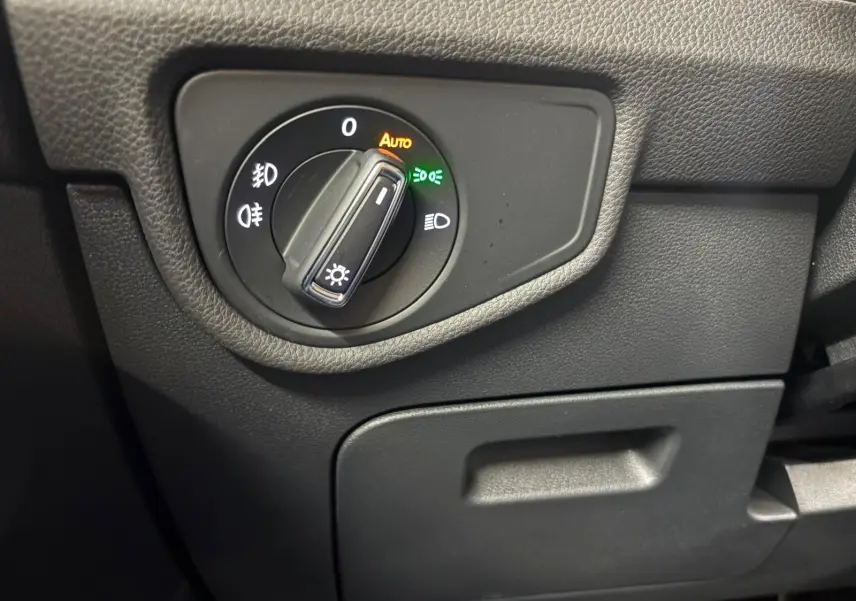 Gros plan sur le bouton de commande des phares du tableau de bord noir du Volkswagen Touran gris Dauphin 2025.