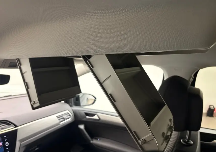 Intérieur du Volkswagen Touran gris Dauphin, vue côté passager avec deux rangements plafond ouverts au-dessus des sièges.