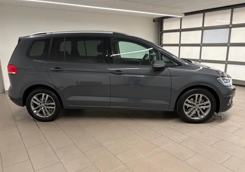 Volkswagen Touran 2.0 TDI gris dauphin vu de profil côté gauche, avec jantes alliage et attelage escamotable.