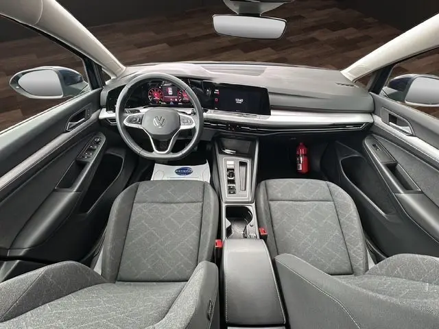 Vue intérieure avant de la Volkswagen Golf VIII 2023 avec tableau de bord numérique, volant multifonction et sièges tissu gris.