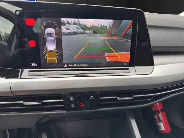Écran central de la Volkswagen Golf VIII bleu montrant la caméra de recul avec guidage de trajectoire en stationnement.