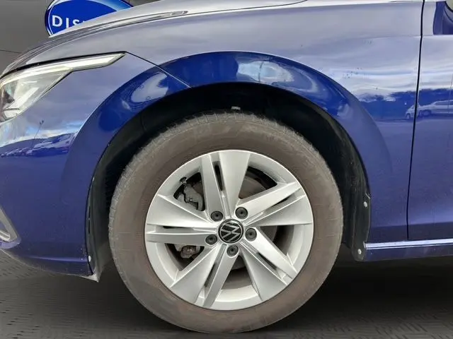 Gros plan sur la roue avant gauche d'une Volkswagen Golf VIII bleu métallisé avec jante alliage cinq branches.