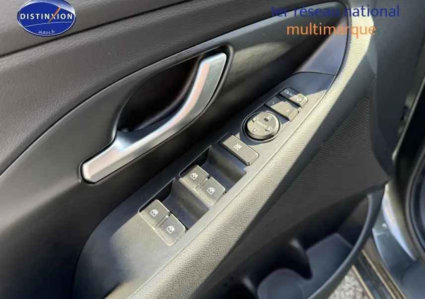 Gros plan sur la commande des vitres côté conducteur d'une Hyundai i30 gris anthracite 2024.
