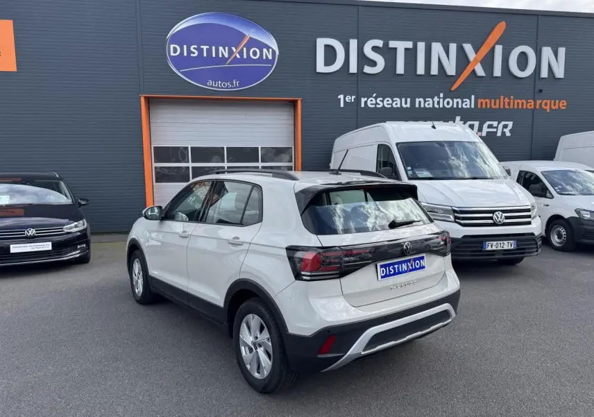 Volkswagen T-Cross gris Ascot vue 3/4 arrière droit sur parking devant un bâtiment Distinxion.