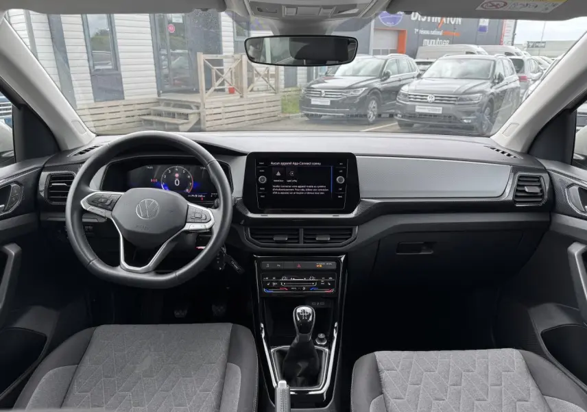 Vue intérieure du tableau de bord et volant du Volkswagen T-Cross 2024 avec écran digital et sellerie grise.