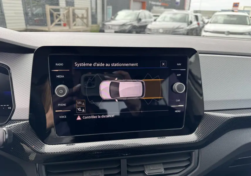 Écran tactile du système d'aide au stationnement dans un Volkswagen T-Cross gris Ascot, vue intérieure avant.