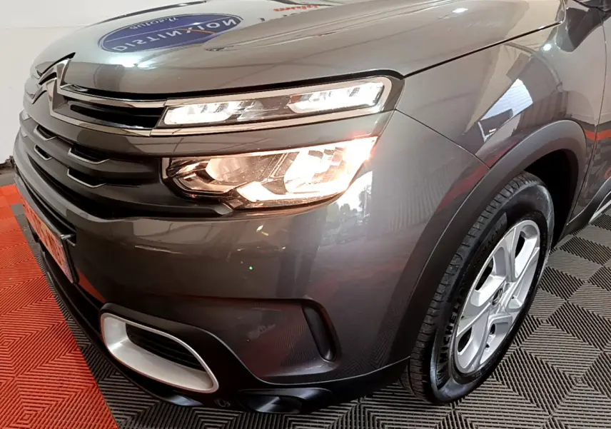 Vue 3/4 avant droit d'une Citroën C5 Aircross gris foncé avec feux allumés et jantes alliage 17 pouces.