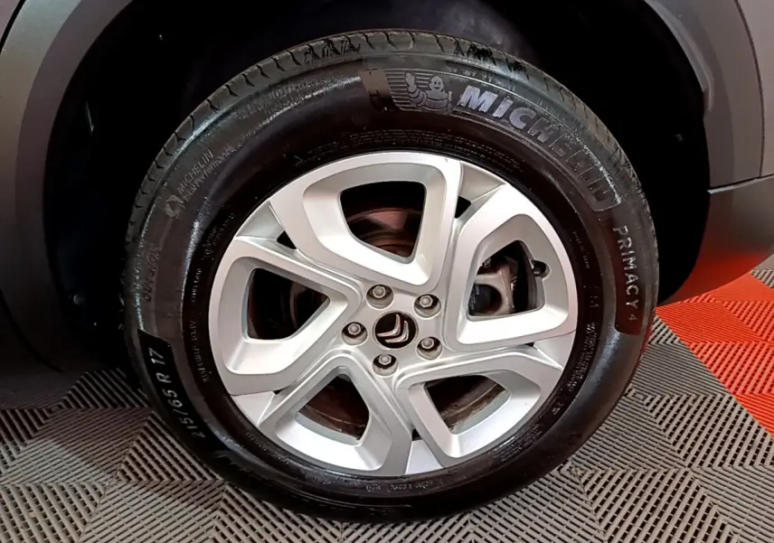 Gros plan sur la jante alliage 17 pouces argentée et pneu Michelin du côté avant droit du Citroën C5 Aircross gris foncé.