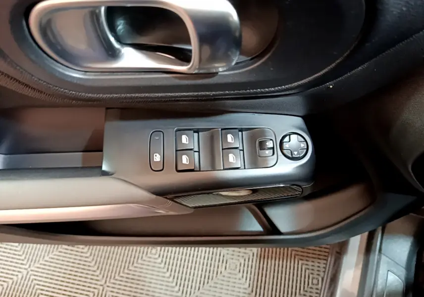 Vue rapprochée du panneau de commandes des vitres et rétroviseurs côté conducteur d'une Citroën C5 Aircross gris foncé de 2020.