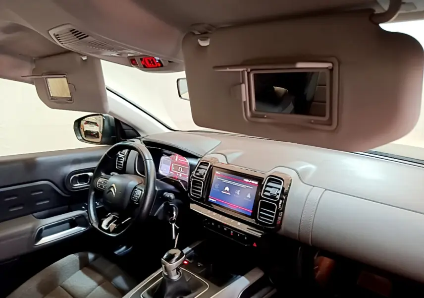 Vue intérieure avant gauche du Citroën C5 Aircross gris foncé, volant cuir Mistral et écran tactile central allumé.