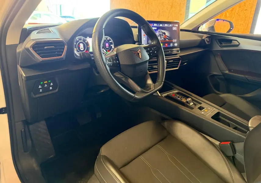 Vue intérieure côté conducteur du CUPRA LEON ST blanc 2024, avec tableau de bord numérique et écran tactile central.