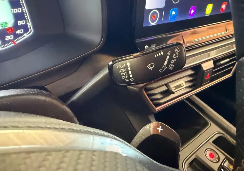 Détail intérieur du tableau de bord côté gauche de la CUPRA LEON ST 2024, avec commandes essuie-glace et écran tactile.