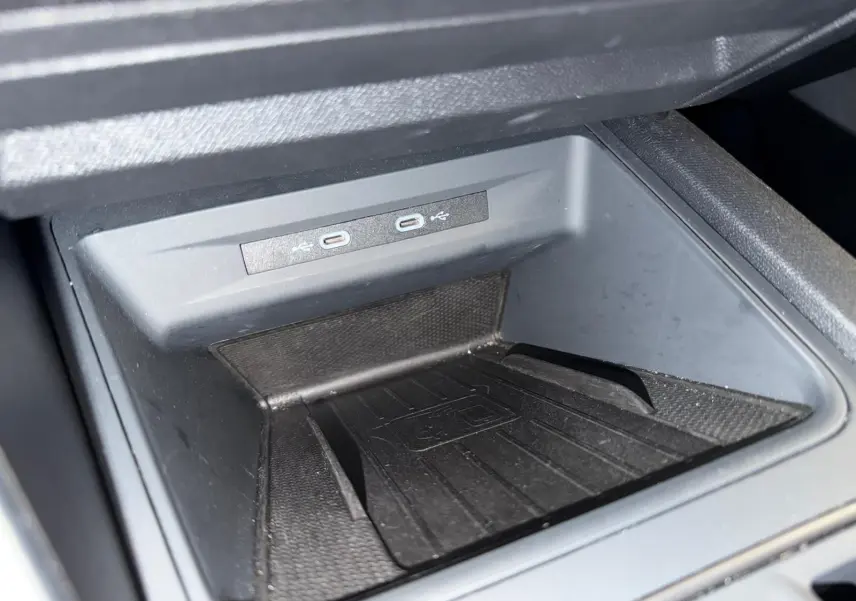 Gros plan sur le compartiment de recharge sans fil noir avec deux ports USB-C dans une CUPRA LEON ST blanche 2024.
