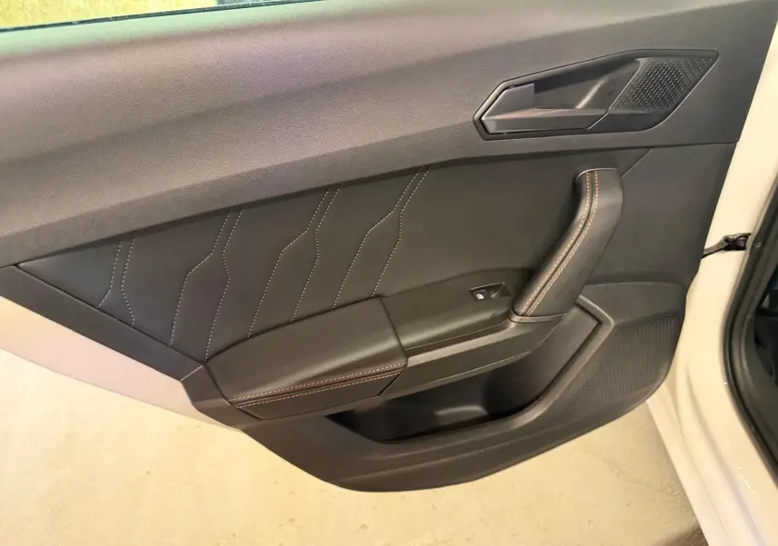 Vue intérieure côté gauche de la porte avant blanche d'une CUPRA LEON ST 2024 avec garniture noire et surpiqûres contrastantes.