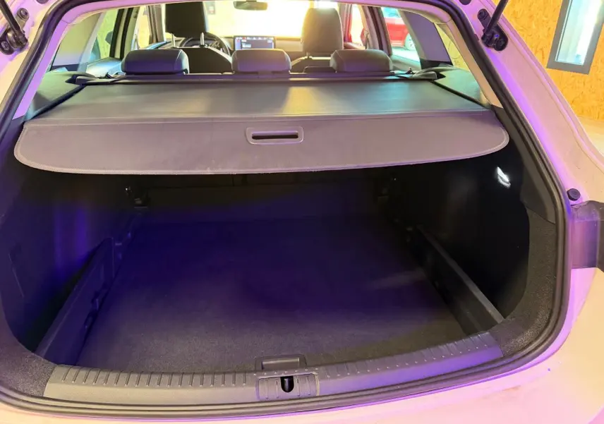 Vue arrière du coffre ouvert d'une CUPRA LEON ST blanche 2024, avec cache-bagages et intérieur noir visible.