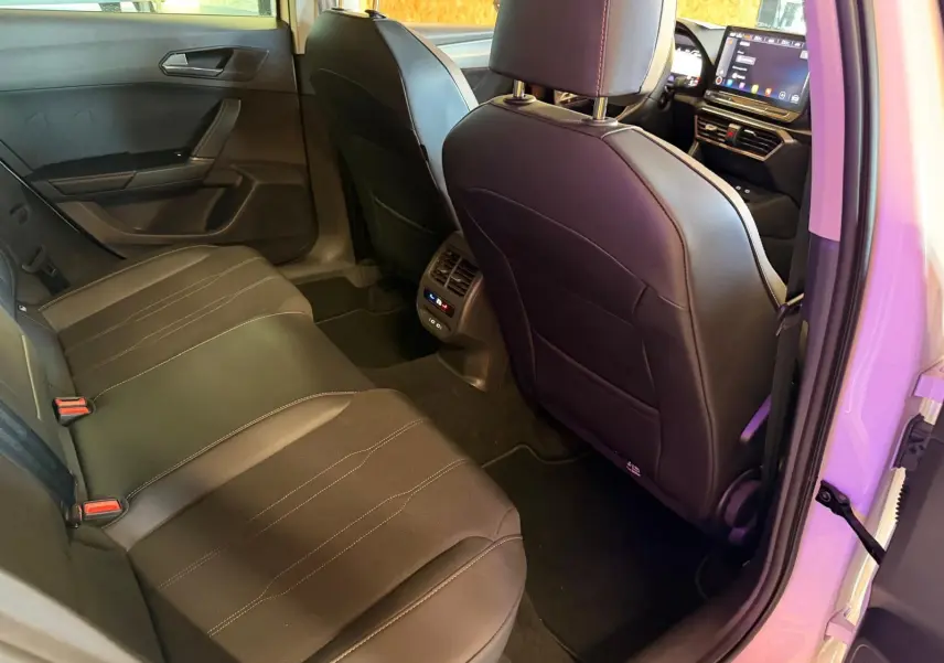 Vue intérieure arrière droite de la CUPRA LEON ST 2024 blanche, montrant les sièges noirs et la console centrale avec commandes climatisation.