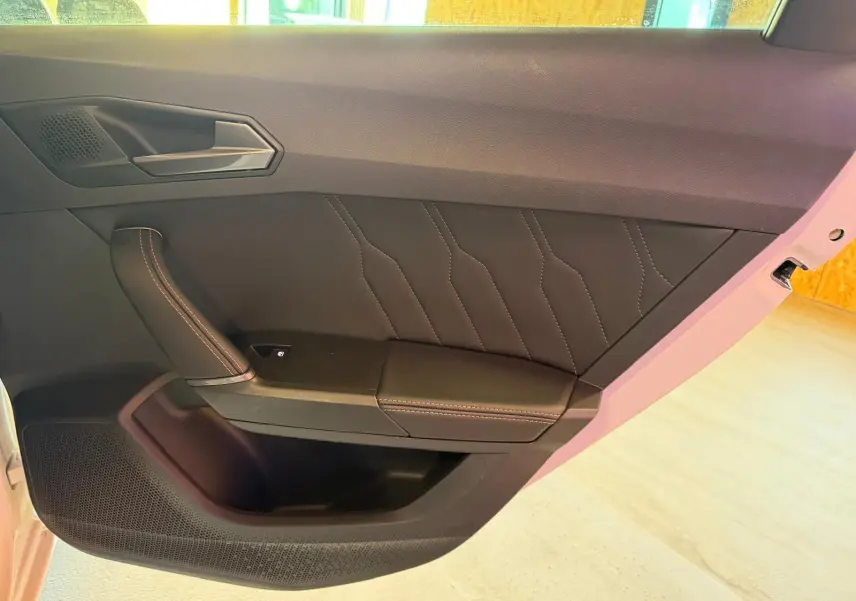 Vue intérieure côté gauche de la porte avant d'une CUPRA LEON ST blanche avec finition cuir noir et surpiqûres contrastées.
