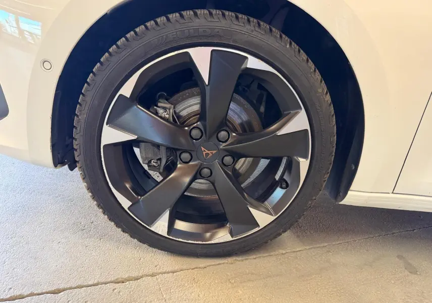 Gros plan sur la roue avant droite d’une CUPRA LEON ST blanche avec jante noire à cinq branches.