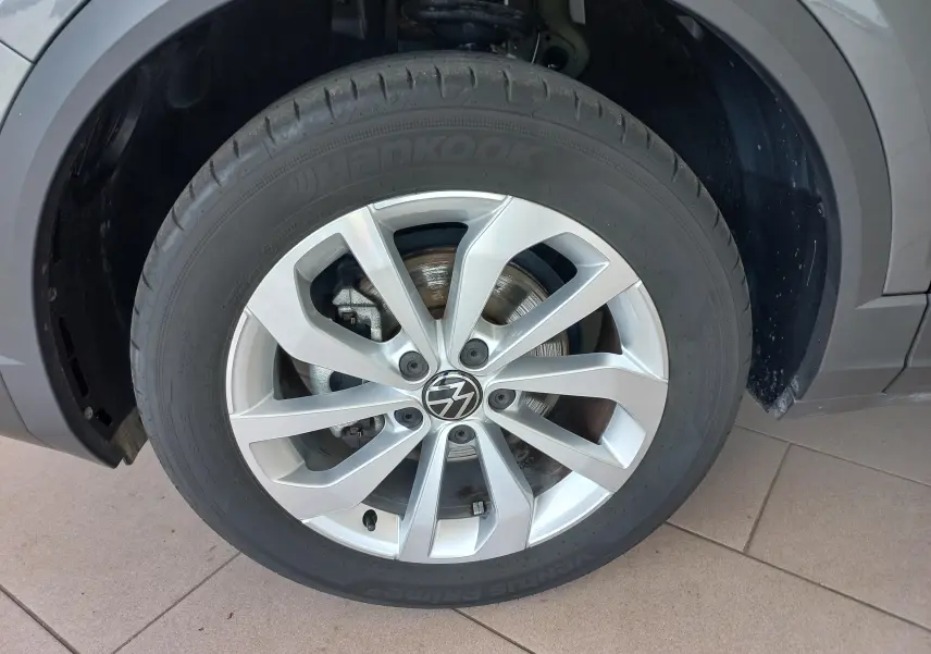 Gros plan sur la roue avant gauche du Volkswagen T-Roc 2025 gris Indium, mettant en valeur la jante alliage et le pneu Hankook.