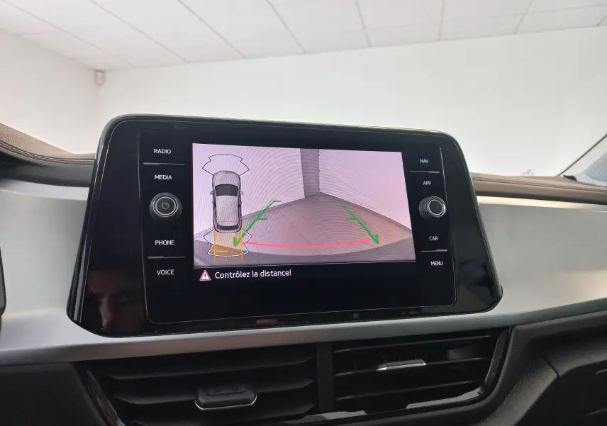 Écran central du Volkswagen T-Roc 2025 montrant la caméra de recul avec alertes de distance, intérieur gris et noir.