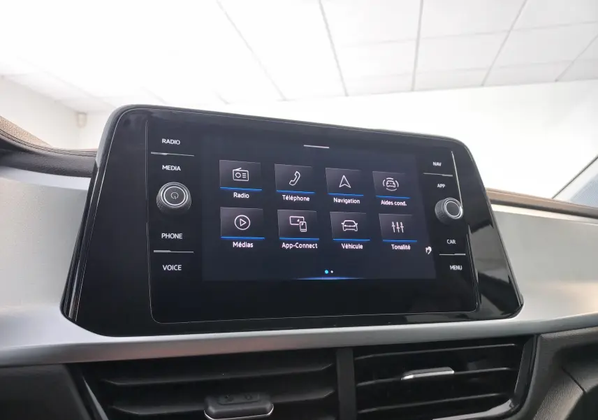 Écran tactile central du Volkswagen T-Roc 2025 gris Indium, affichant le menu principal avec options multimédia et navigation.