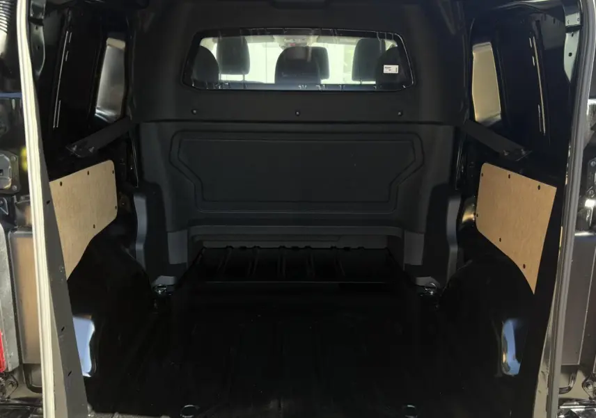 Vue intérieure arrière du Citroën Jumpy noir Perla, montrant l'espace de chargement vide et les panneaux latéraux en bois clair.