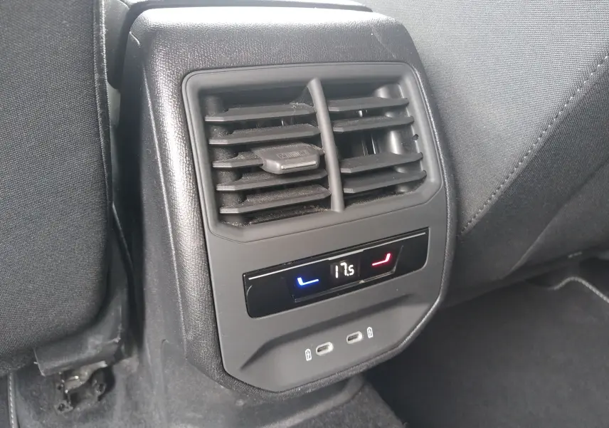 Gros plan sur la console arrière de la SEAT LEON ST grise 2022, avec bouches d’aération, affichage digital de la climatisation et ports USB.