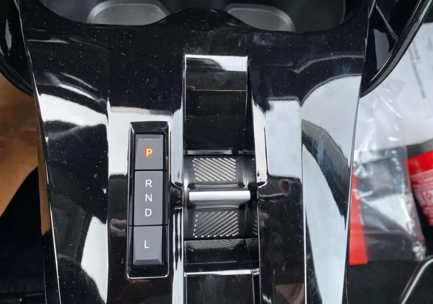 Gros plan sur la console centrale noire brillante avec sélecteur de boîte auto et bouton P allumé du Citroën C3 Aircross 2025.