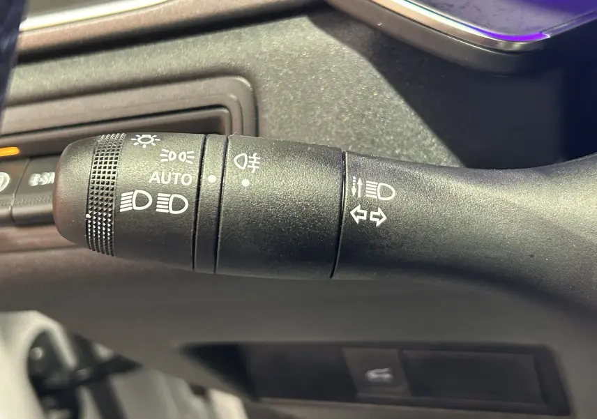 Gros plan sur la commande de phares et clignotants noire dans l'habitacle du Renault Symbioz blanc nacré 2025.