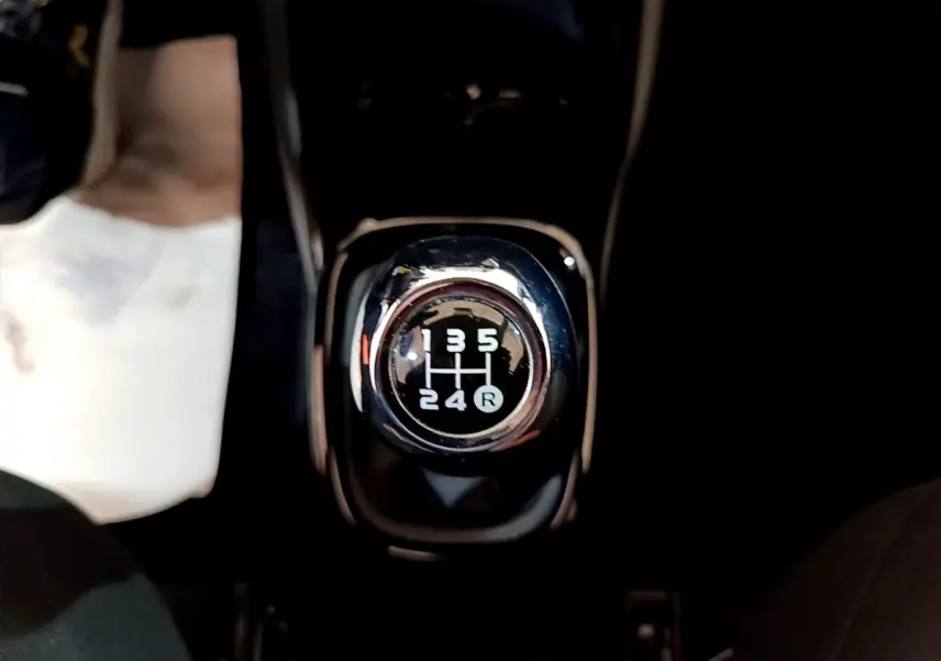 Gros plan sur le levier de vitesses manuel noir et chrome de la Citroën C1 Shine gris clair, intérieur sombre.