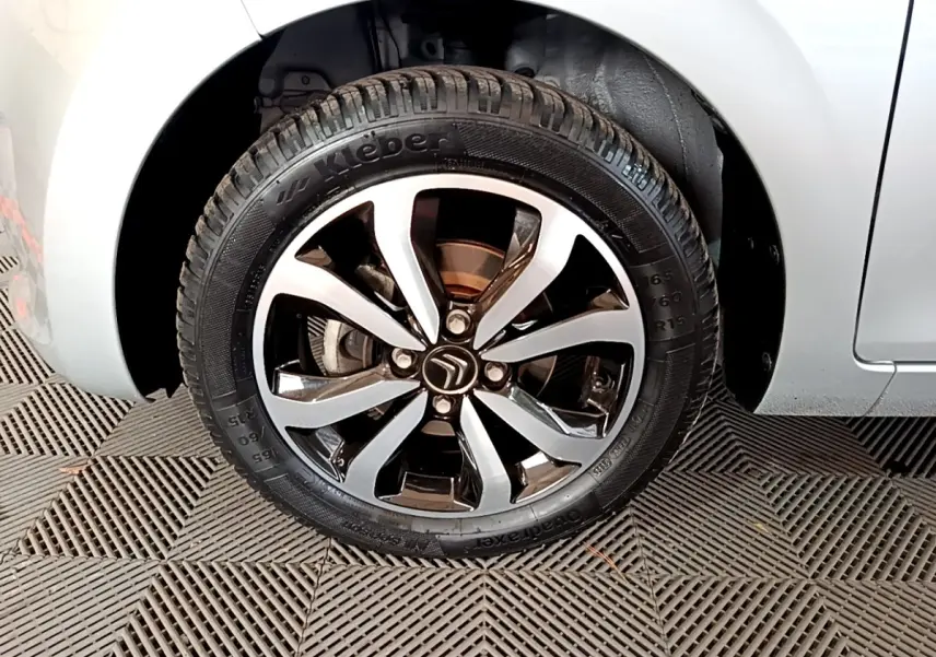 Gros plan sur la roue avant droite gris clair de la Citroën C1 avec jante alliage noire et argentée.