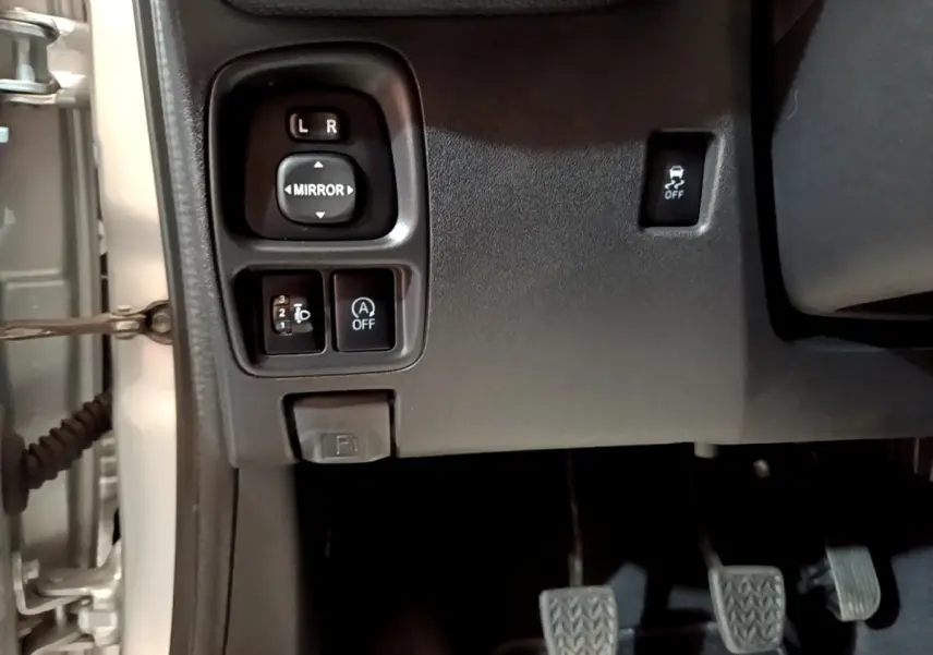 Vue intérieure côté gauche du tableau de bord gris clair d'une Citroën C1 avec commandes des rétroviseurs et pédales visibles.