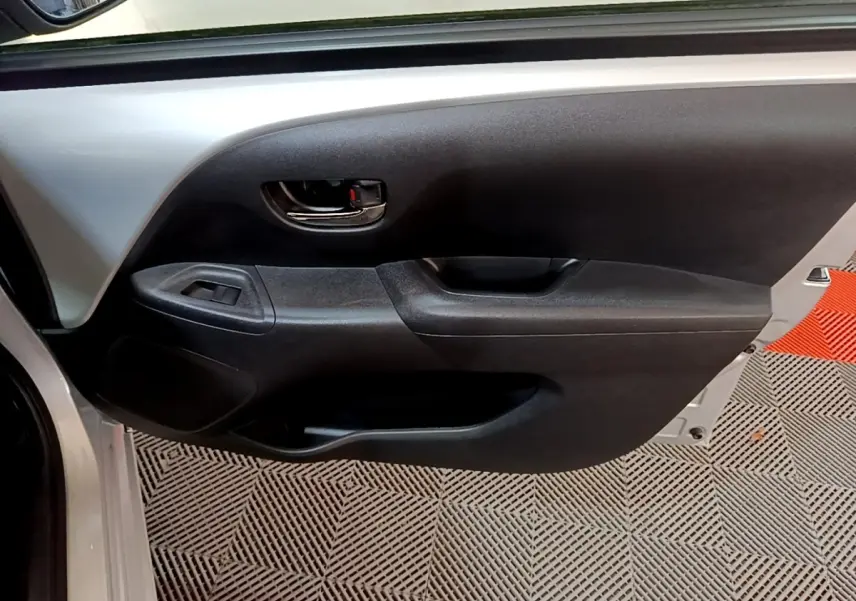 Vue rapprochée de la porte avant gauche gris clair de la Citroën C1 avec poignée intérieure noire et commande de vitre.