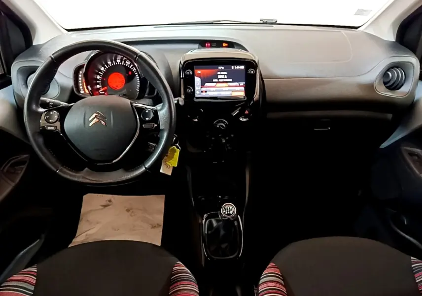 Intérieur de Citroën C1 2019 vue de face, tableau de bord noir avec écran tactile et volant cuir multifonctions.