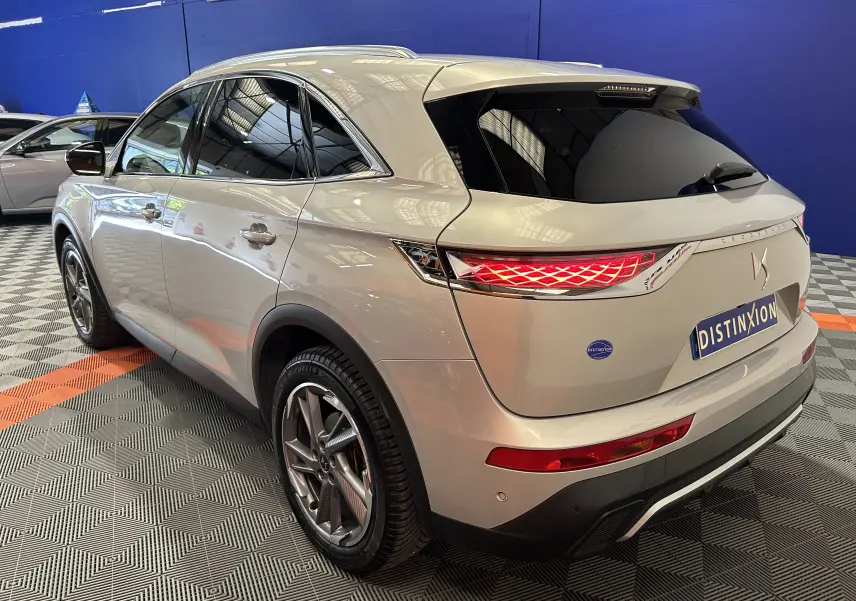 Vue 3/4 arrière droite du DS7 Crossback bleu cristal pearl, avec feux arrière allumés et jantes alliage distinctives.