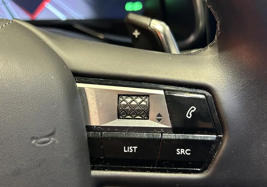 Gros plan sur les commandes noires et argentées du volant du DS7 Crossback, avec molette texturée et boutons LIST et SRC.