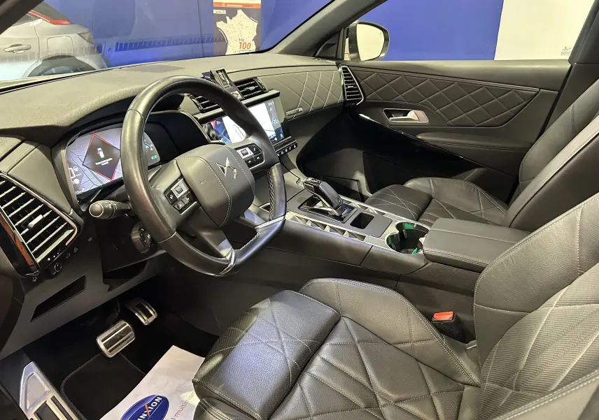 Vue intérieure côté conducteur du DS7 Crossback avec sellerie cuir noire matelassée et tableau de bord moderne.