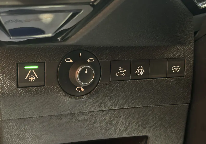 Gros plan sur les commandes intérieures noires du DS7 Crossback 2022, avec témoin vert allumé sur l'assistance au maintien de voie.