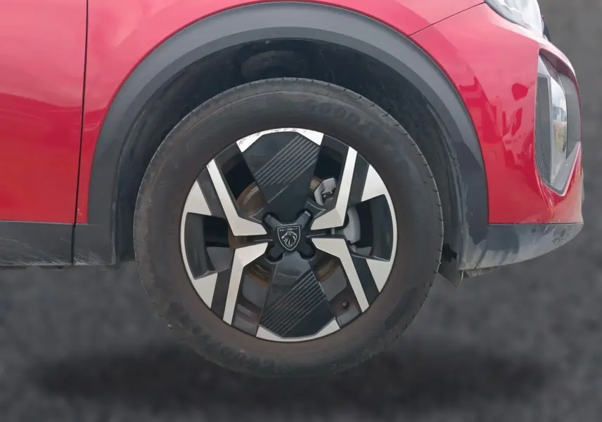 Gros plan sur la roue avant droite du Peugeot 2008 rouge elixir avec jante alu au design moderne.