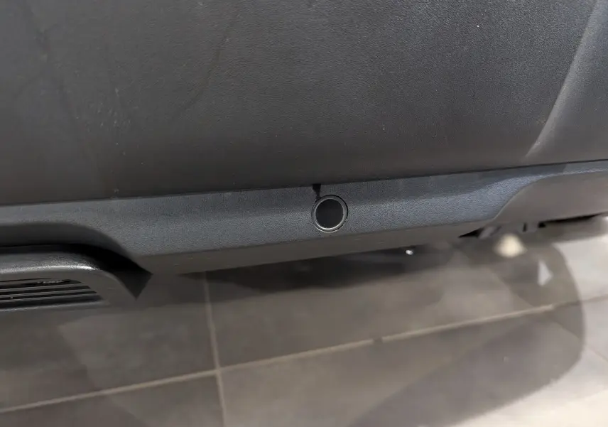 Gros plan sur un capteur de stationnement noir intégré au pare-chocs arrière du Peugeot 3008 blanc Glacier toit noir.