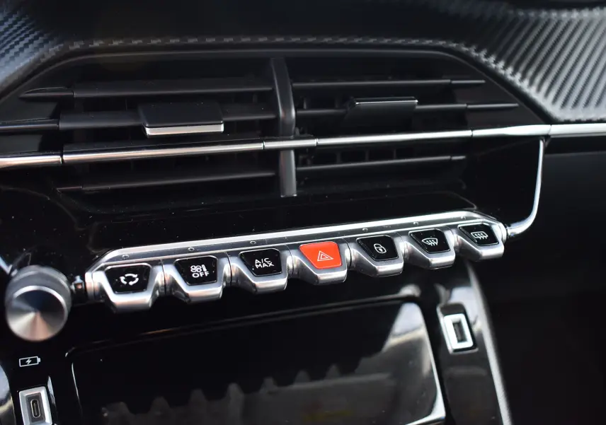 Gros plan sur la console centrale du Peugeot 2008 bleu 2021, mettant en valeur les commandes et aérateurs noirs brillants.