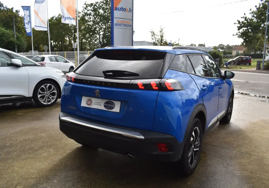 Peugeot 2008 BlueHDi 110 diesel bleu vue 3/4 arrière droit, avec feux arrière à griffes et toit noir.