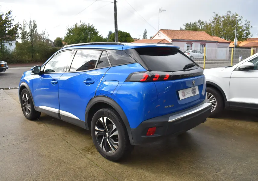 Vue 3/4 arrière droite d'un Peugeot 2008 bleu 2021 avec feux arrière à griffes et jantes alliage noires.