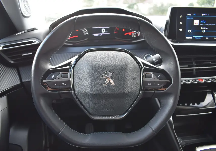 Vue rapprochée du volant cuir noir du Peugeot 2008 BleuHDI 110 2021 avec commandes intégrées et tableau de bord numérique.