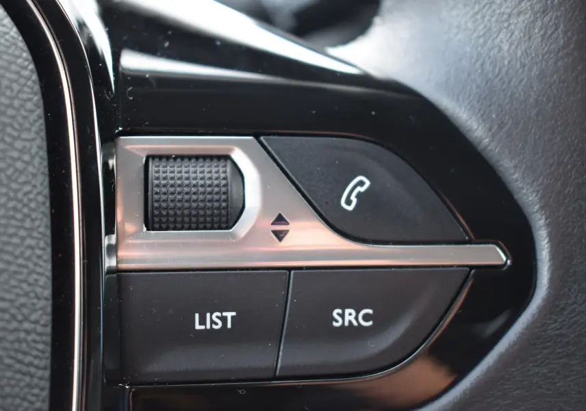 Gros plan sur les commandes au volant du Peugeot 2008 bleu, avec boutons LIST, SRC et téléphone intégré.