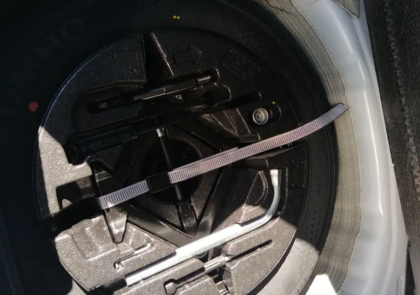 Gros plan sur la roue de secours et les outils de bord dans le coffre d'une Volkswagen Polo blanche 2021.