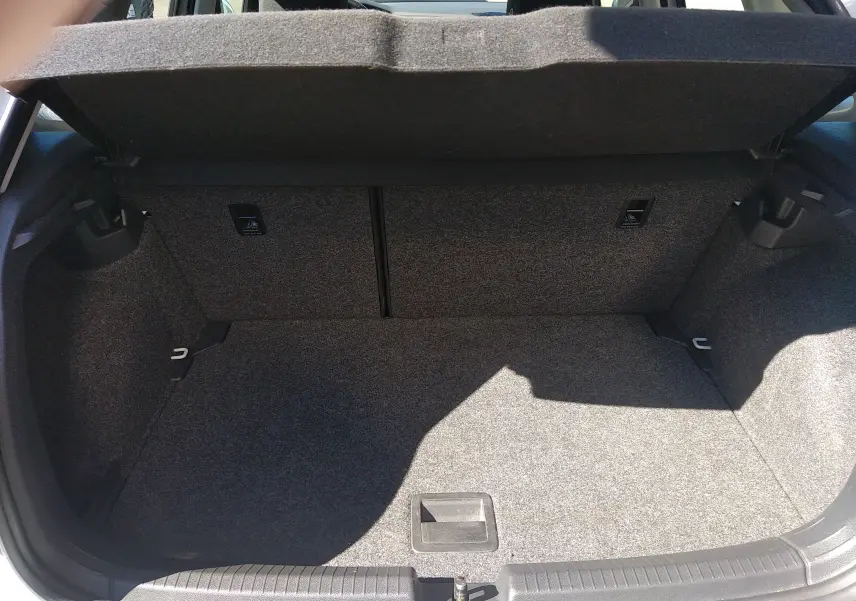 Coffre ouvert de la Volkswagen Polo blanche 2021, vue intérieure montrant l'espace de chargement en tissu gris.