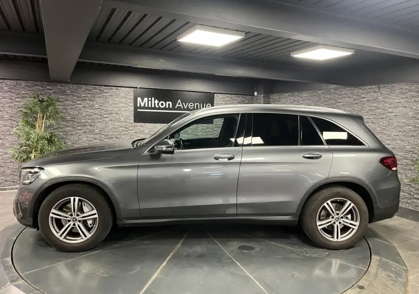 Vue latérale droite d'un Mercedes GLC gris métallisé avec jantes alliage 18 pouces dans un showroom intérieur.