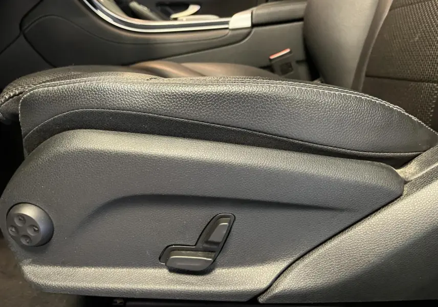 Détail du réglage électrique du siège avant droit en cuir noir dans un Mercedes GLC gris de 2019.